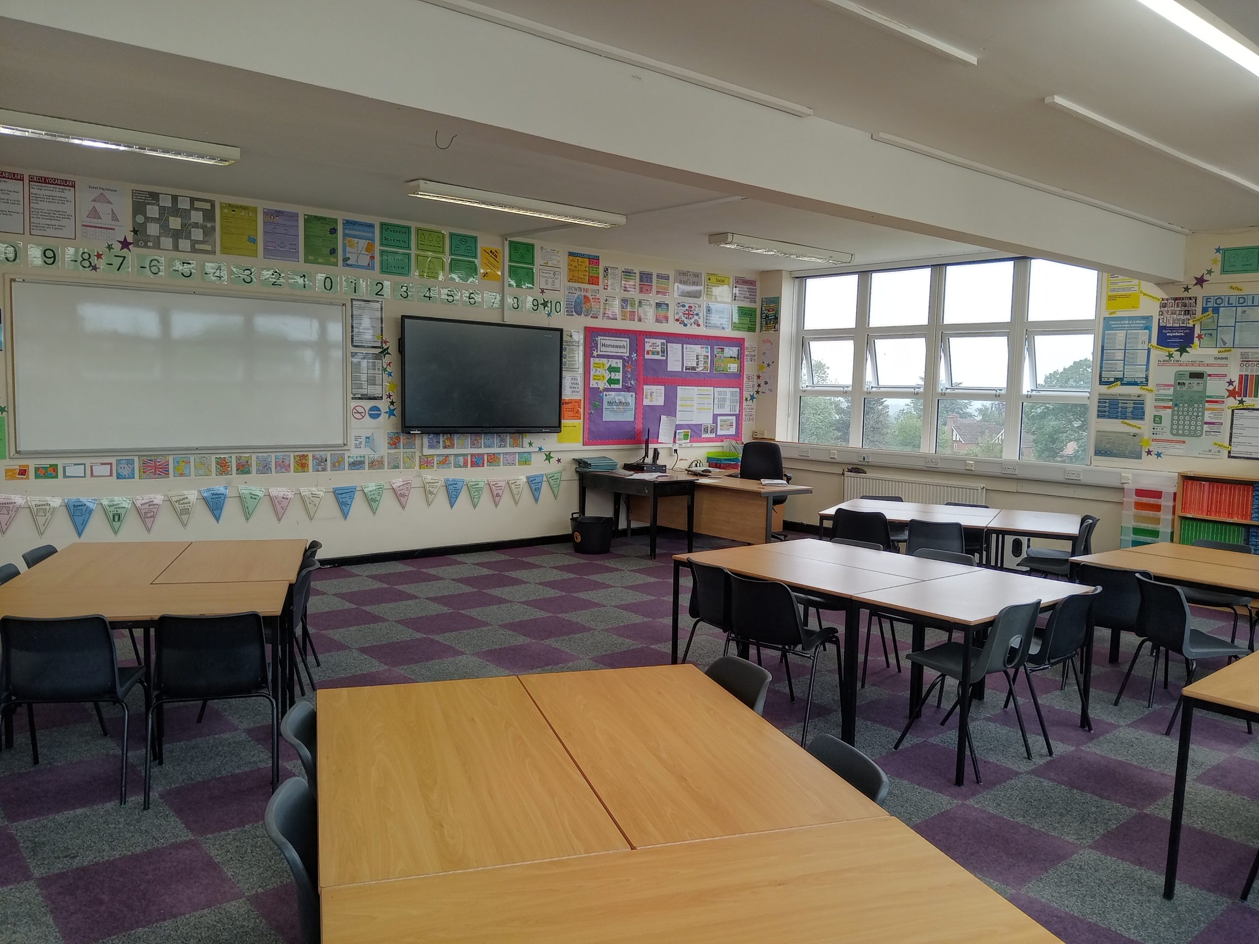 A classroom, viewed from the back, looking towards the board and teacher's desk