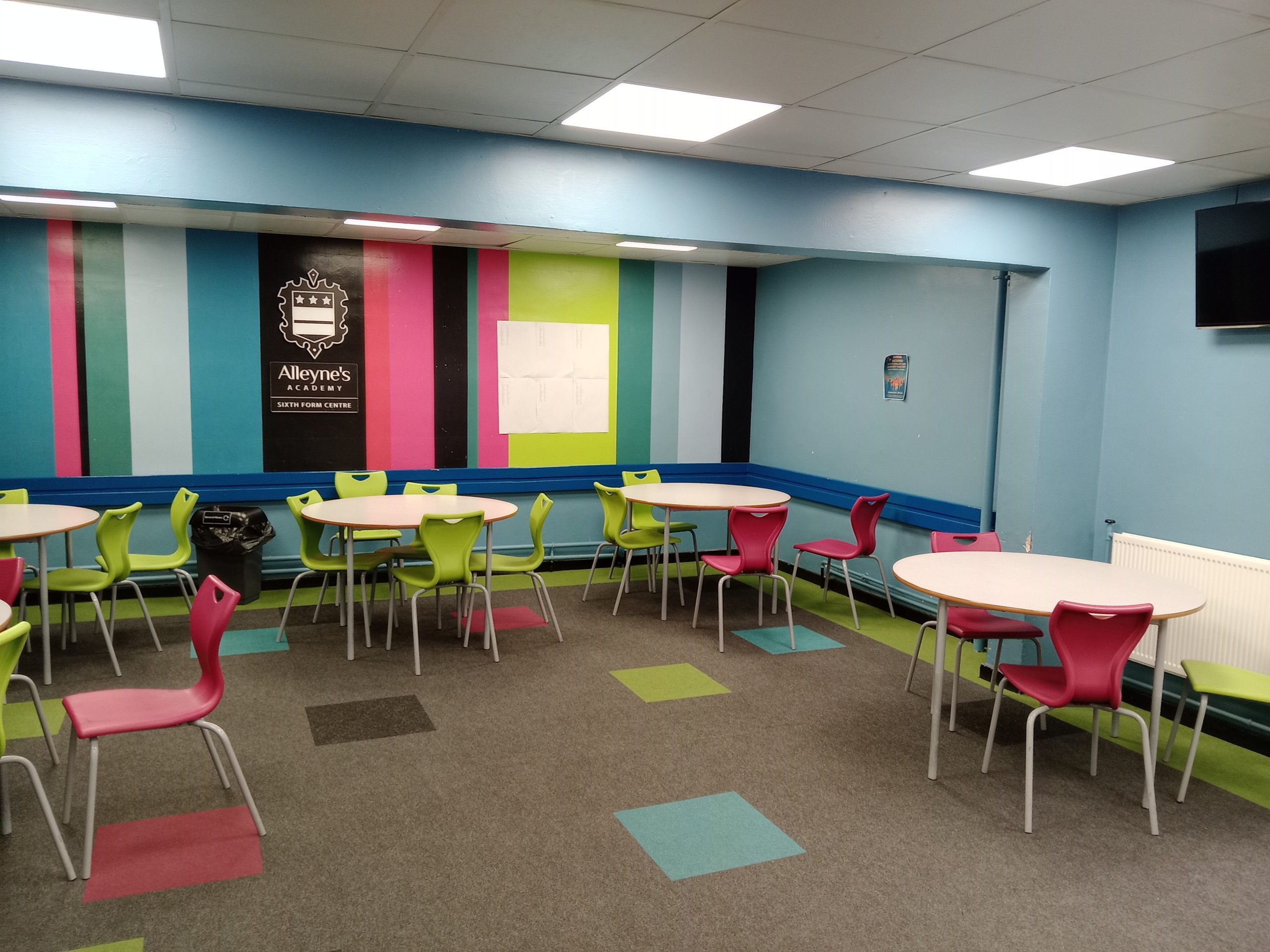 A room with coloured striped walls, set out with tables and chairs