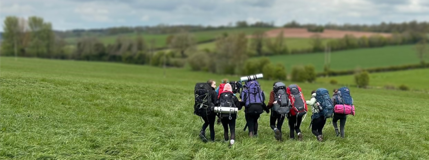 Students hiking across a field on their Duke of Edinburgh expedition